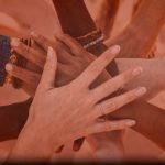 stacked hands with a peach or salmon tint overlay
