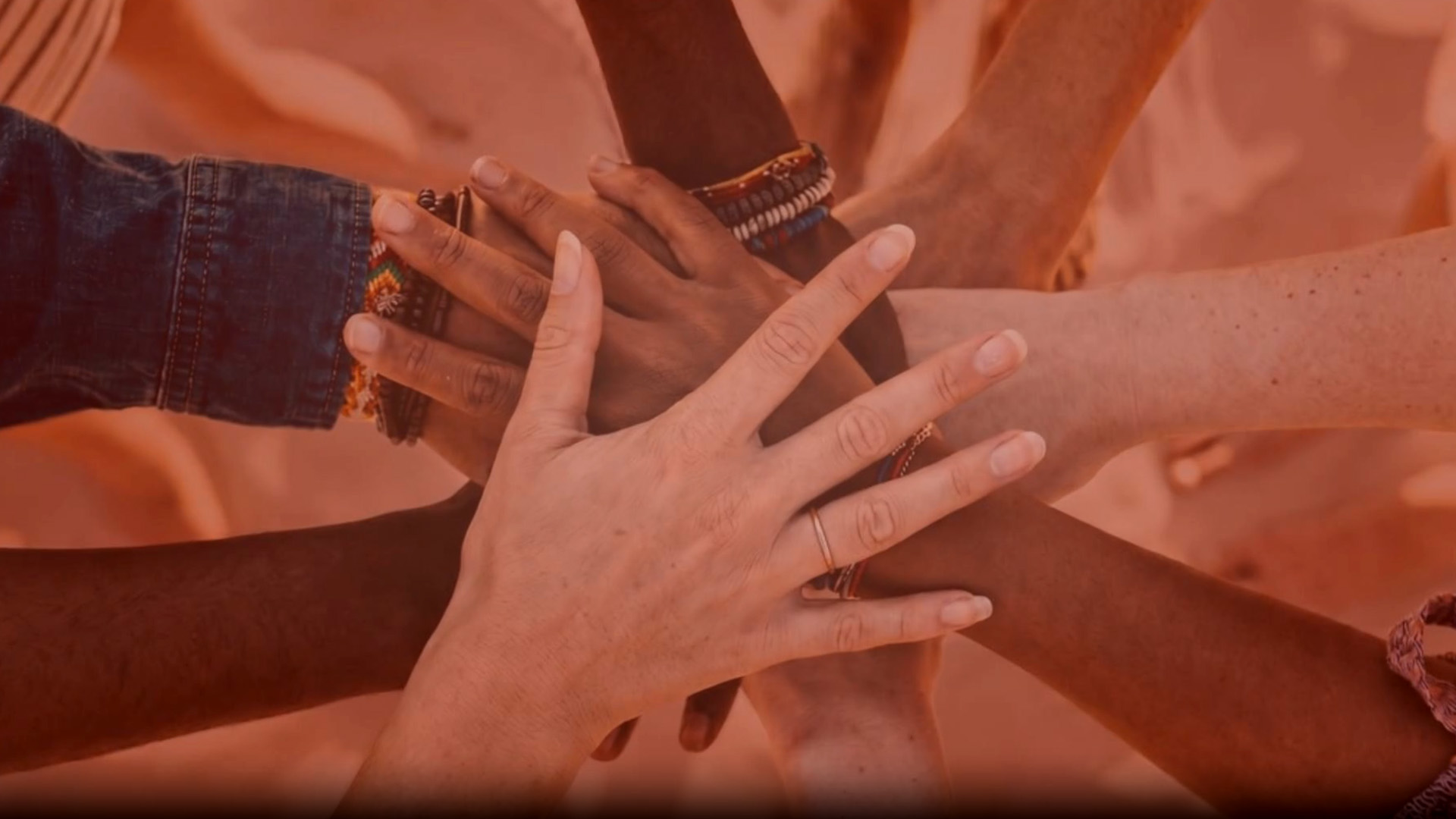 stacked hands with a peach or salmon tint overlay