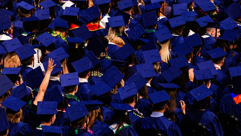 high school graduation with one graduate raising their hand in the middle